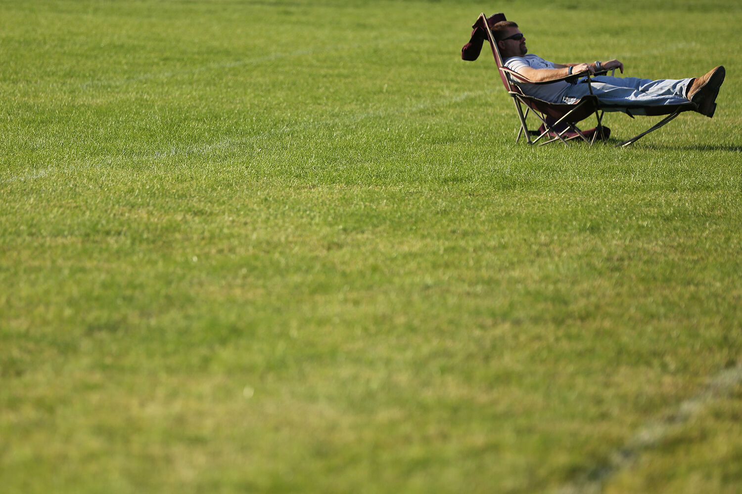 Brad Fox lays out in his lawn chair during his son’s practice